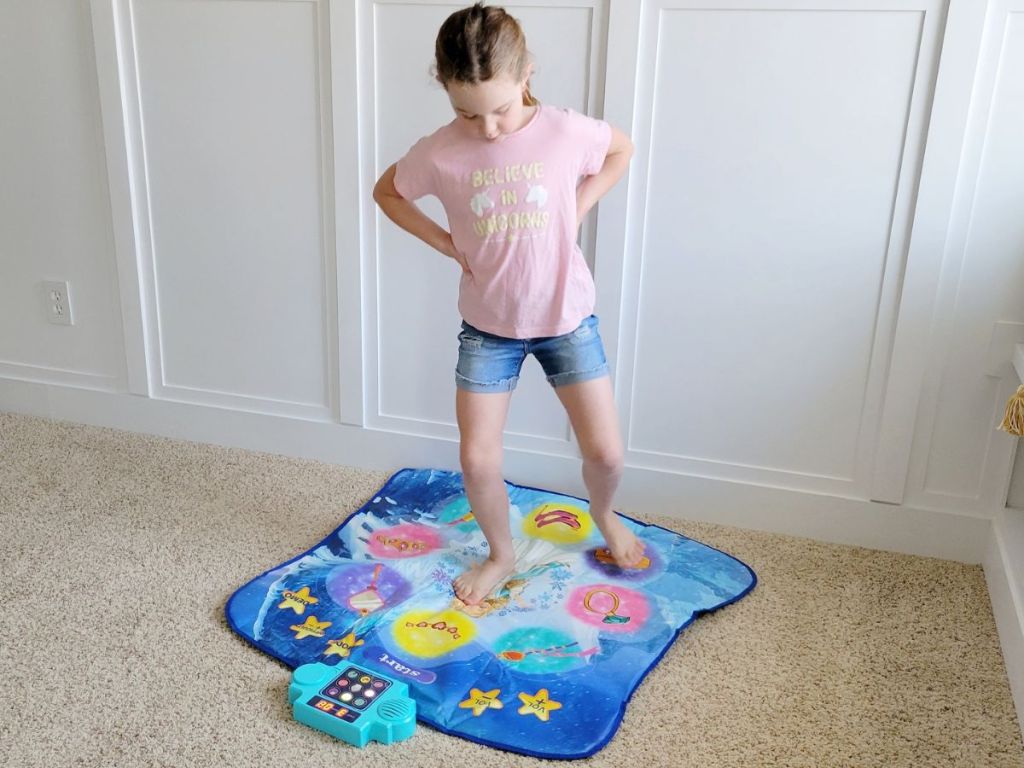 Little girl playing on a dance mat toy trying to get the steps right