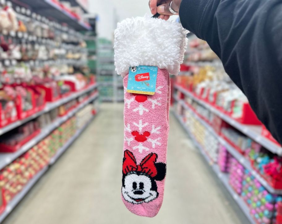 a womans hand holding a pair of Minnie mouse slipper socks