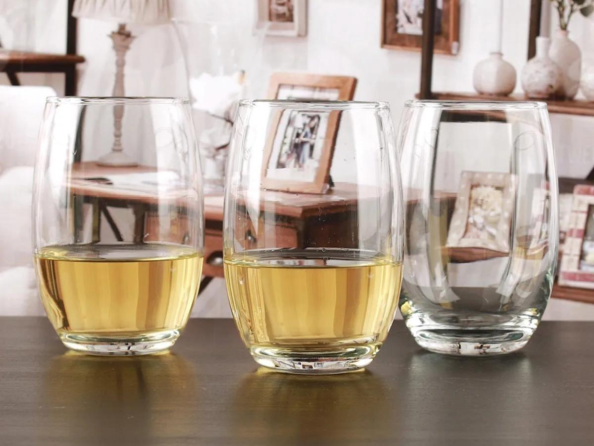 half filled glass drinkware sitting on a wooden table in a room filled with photo frames