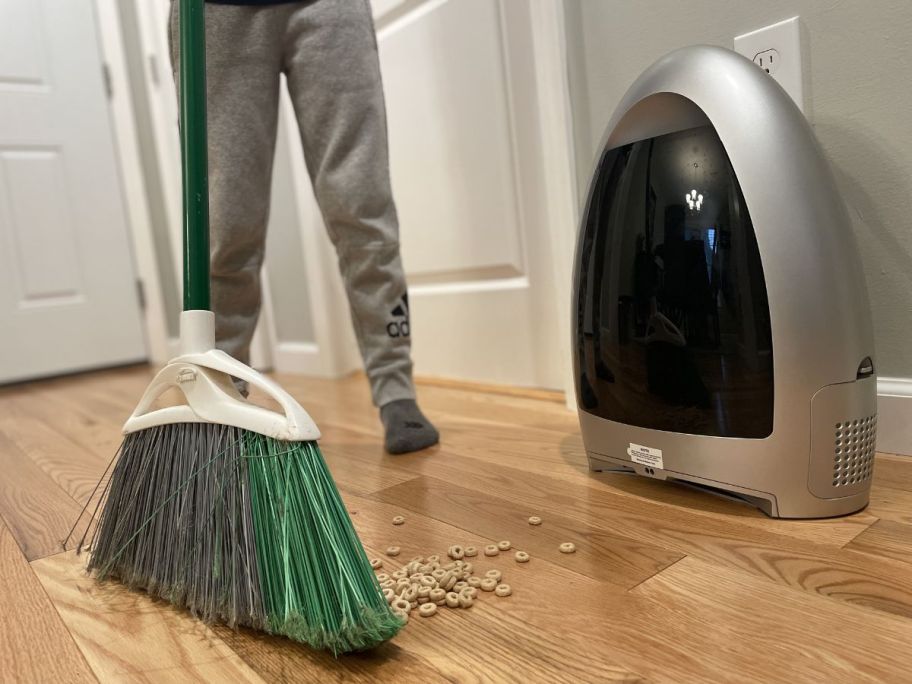 man sweeping cherrios using broom and EyeVac Home Touchless Sensor Activated Vacuum
