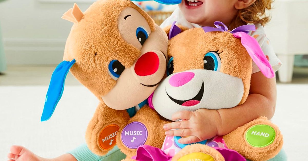 a little girl hugging two Fisher-Price Laugh Learn Smart Stages interactive pups