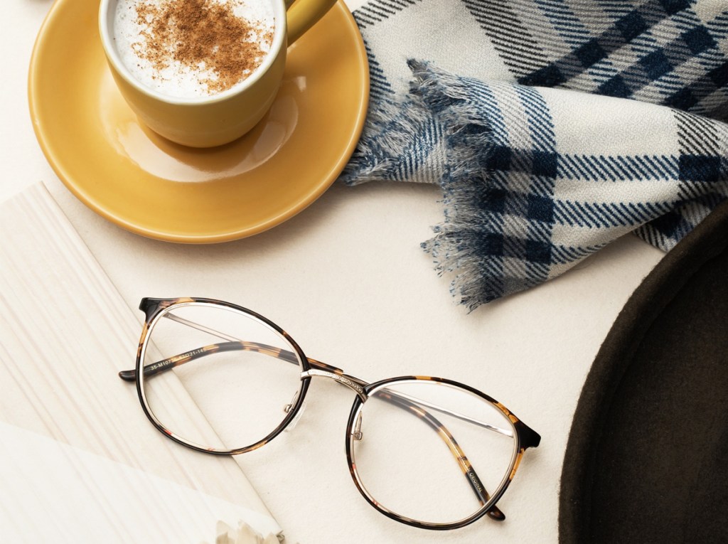pair of glasses near latte and scarf