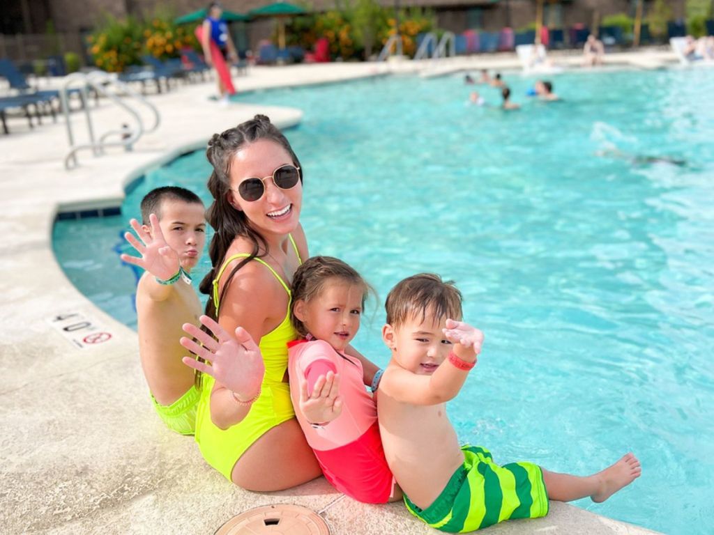 family sitting together on the side of a pool