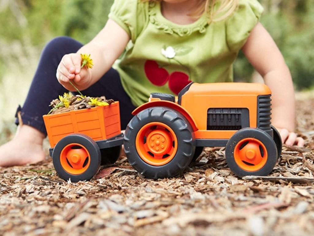 little girl playing with Green Toys Tractor in bark