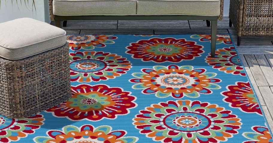 outdoor patio space with large colorful floral medallion outdoor rug and tan wicker furniture