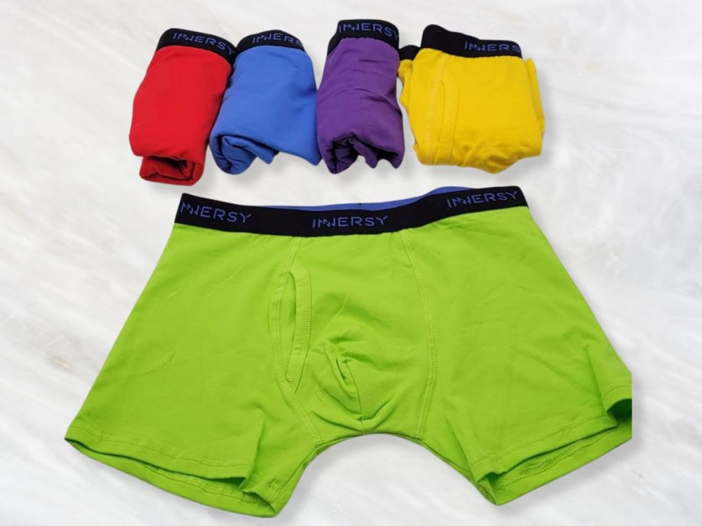 pairs of boys boxer shorts in bright colors, 1 laid out, the others rolled