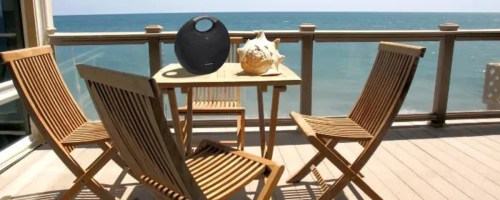Harman Kardon Onyx Studio 6 Speaker on outdoor patio set near beach