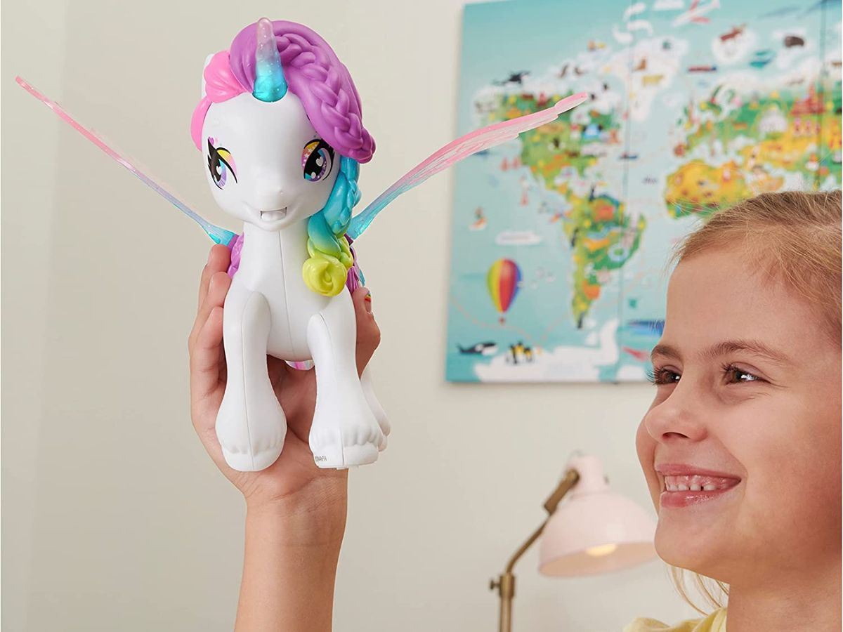 smiling kid holding a hatchimals colleggtibles unicorn toy in the air