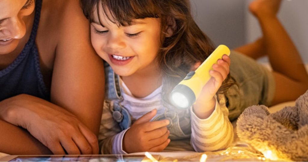 Mom and little girl using an Eveready LED Flashlight to read a book at night
