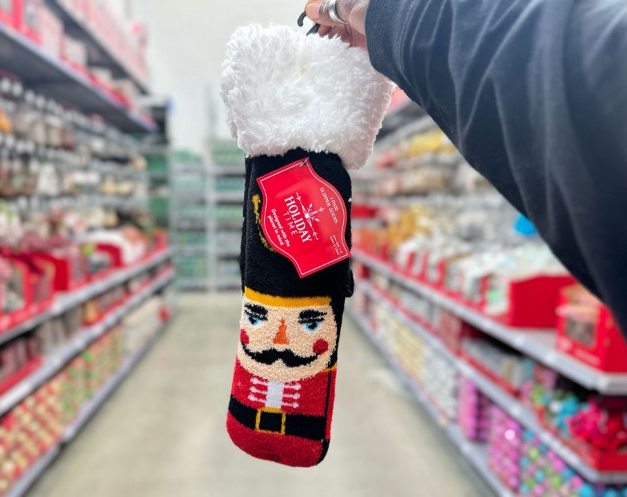 a womans hand holding a pair of nutcracker slipper socks