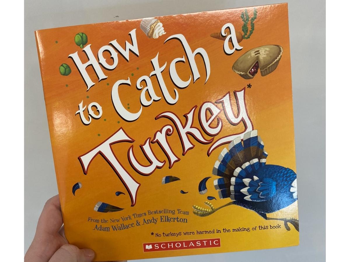 hand holding the corner of a How to Catch a Turkey Hardcover Book
