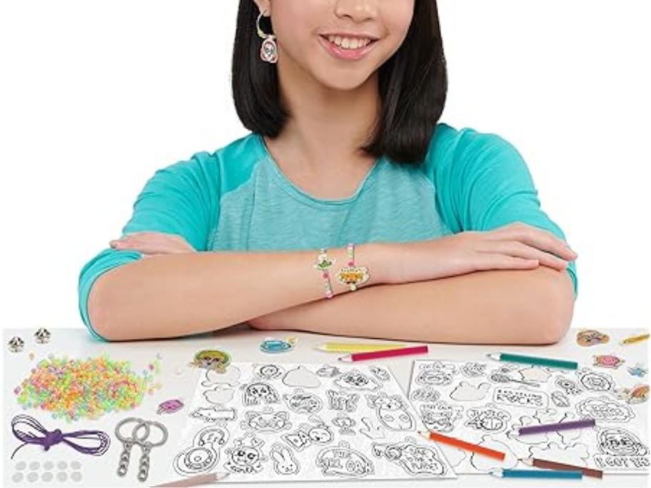 girl sitting in front of Just Play Disney & Pixar Turning Red Deluxe 100-Piece Shrinky Dinks