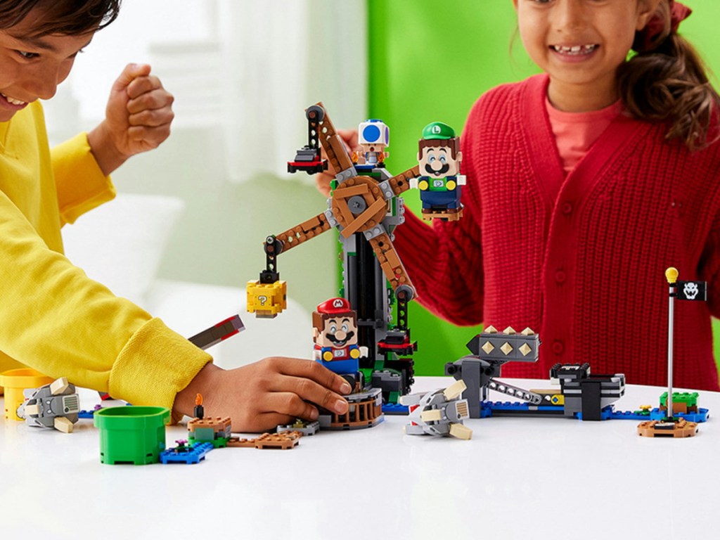two kids playing with a LEGO Super Mario Reznor Knockdown Expansion Set