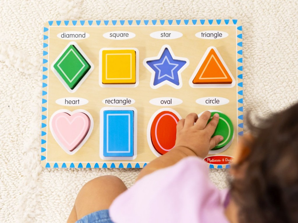 toddler playing with colorful shaped puzzle