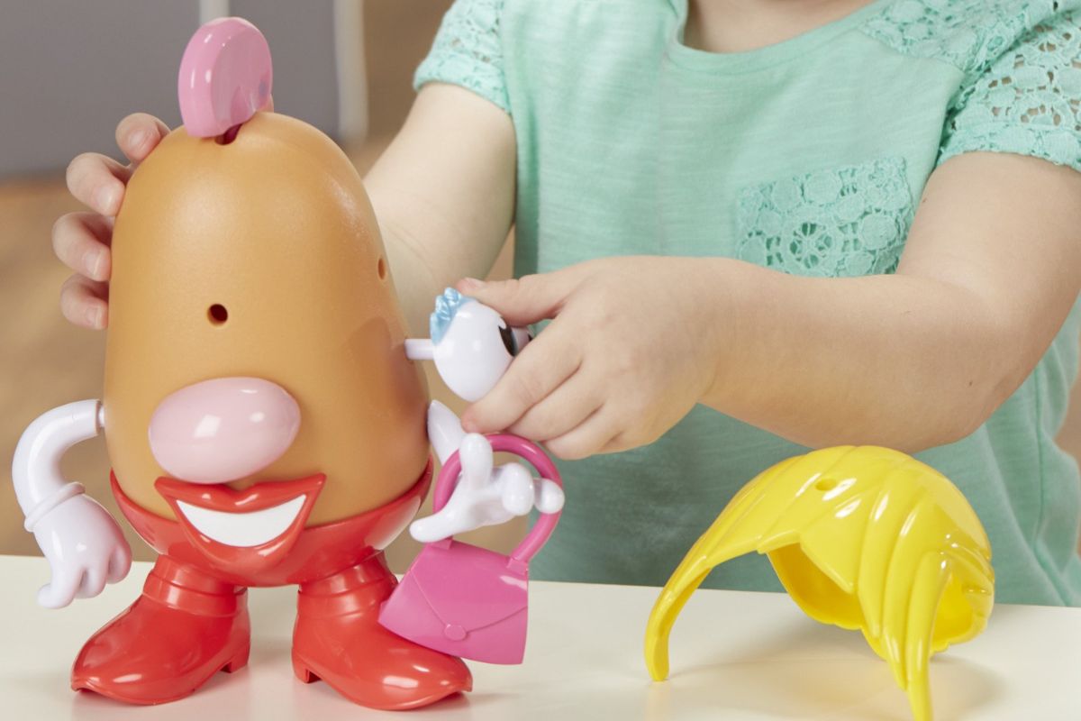 A little girl playing with a Mrs potato head