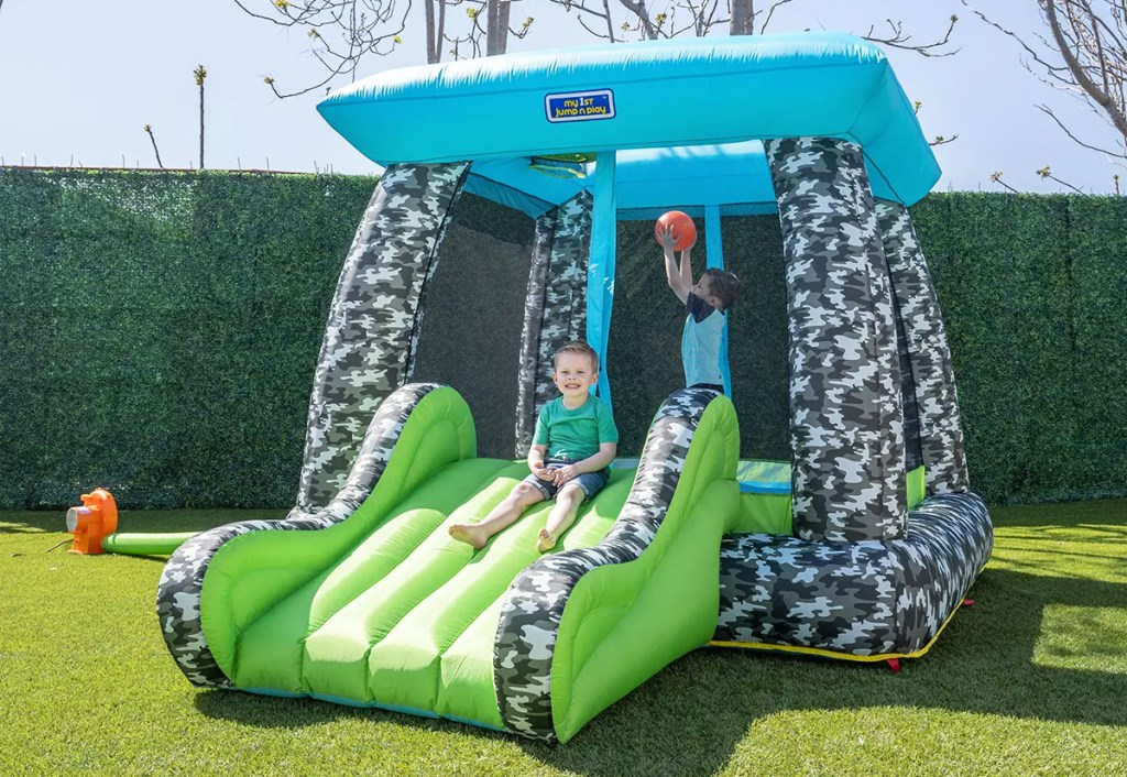 two kids playing on camouflage bounce house