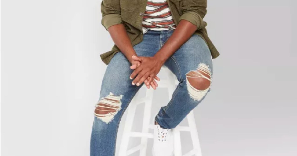 man sitting on white chair in ripped jeans 