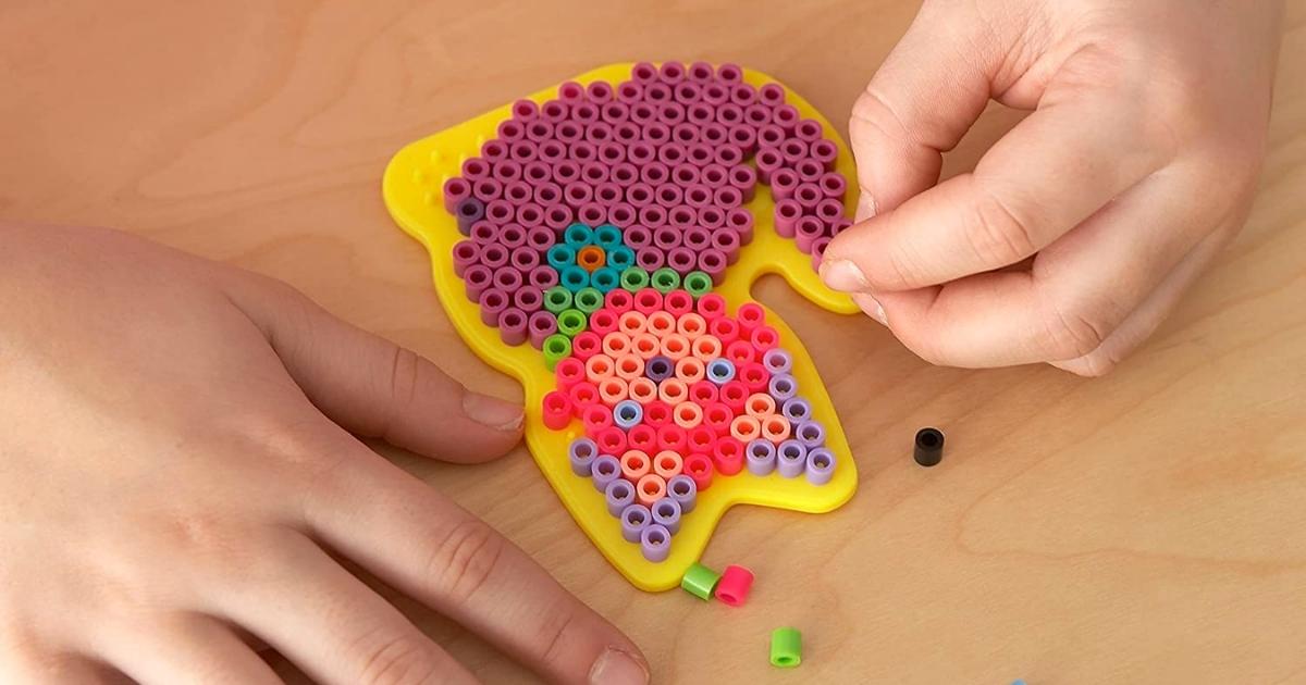 hands placing beads on an animal shaped peg board from a Perler Beads KIt