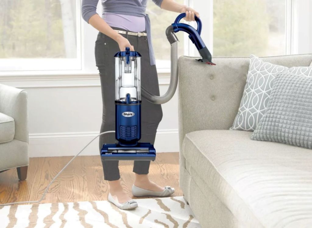 Woman holding a Shark vacuum and cleaning her couch