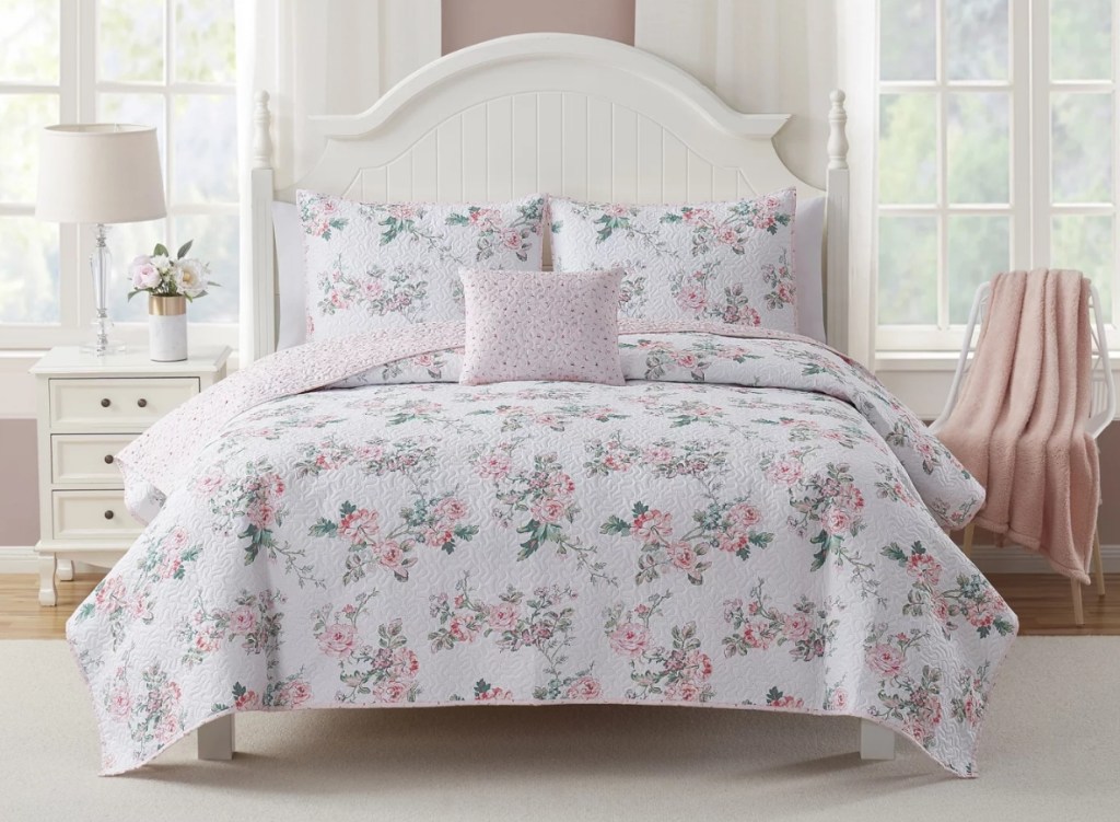 Bedroom with a white bed that has a floral quilt on it