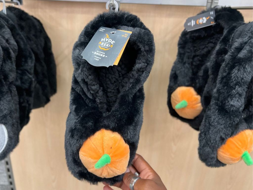  A hand grabbing a black sock with a pumpkin on it. 