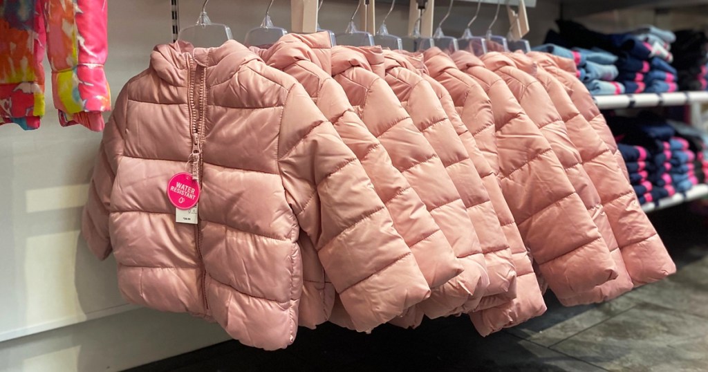 light pink puffer jackets on hangers in store