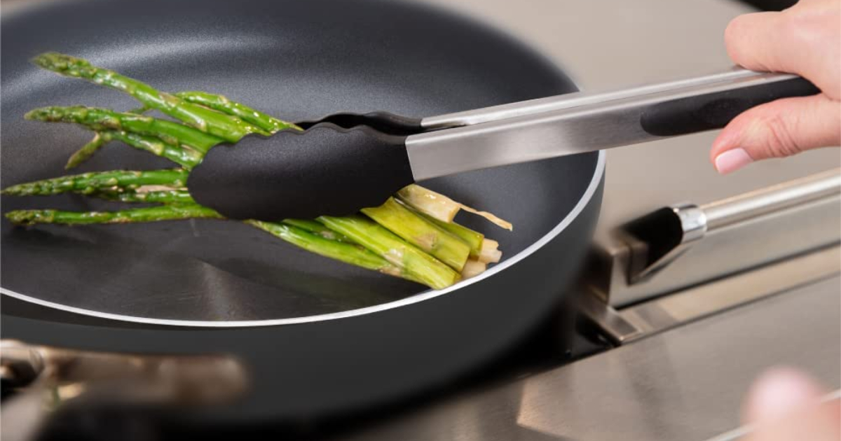 pair of silicone tongs grabbing asparagus out of a pan