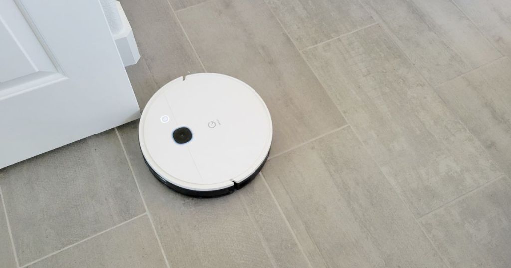 white and black robot vacuum cleaning gray tile floor