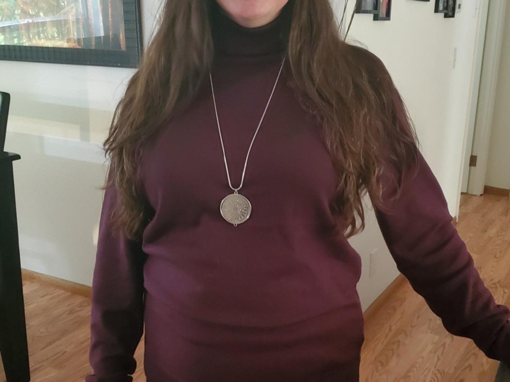 woman wearing maroon turtleneck and medallion necklace
