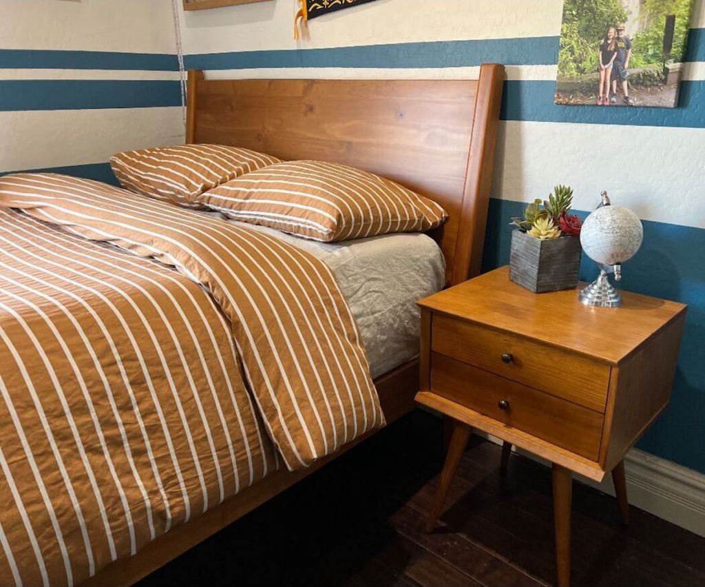 striped bedding on wood bed frame in room