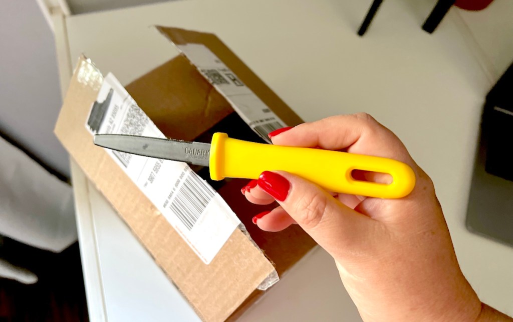hand holding a cutter tool over opened package