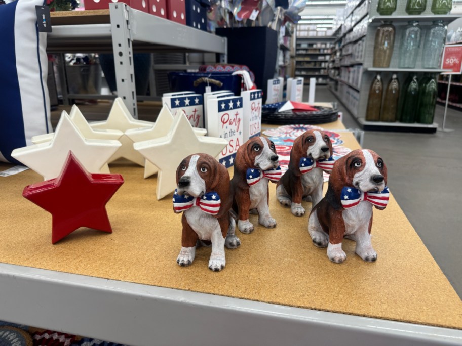 Patriotic store display with four beagle figurines, each with a star-spangled bow tie. Red and white star decorations are nearby.