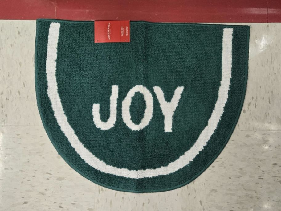 green 'Joy' Christmas Bath Rug on floor in store