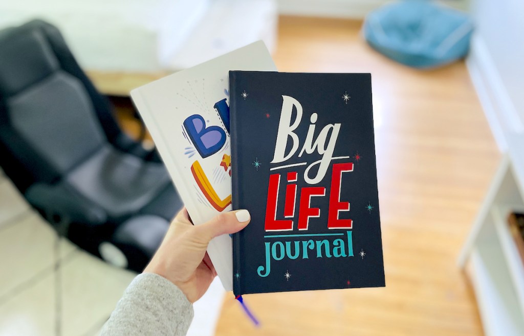 hand holding a big life journal in teens room