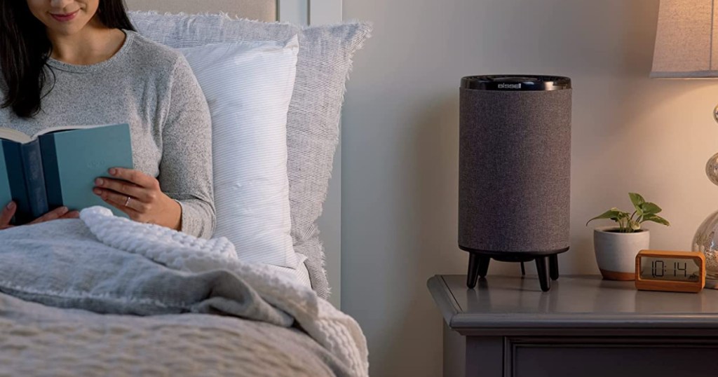 woman reading in bed next to a bissell myair air purifier