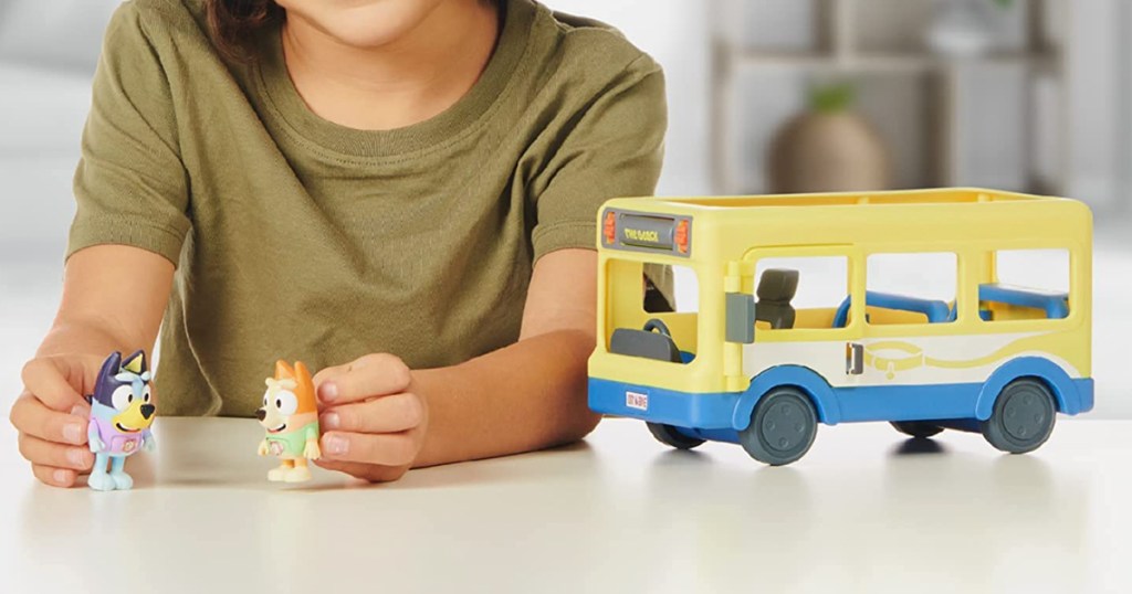 kid playing with bluey figures and bus