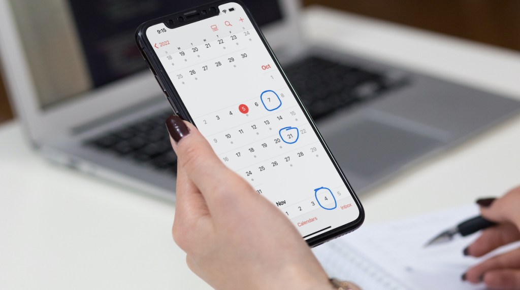 woman holding phone with calendar dates circled on screen