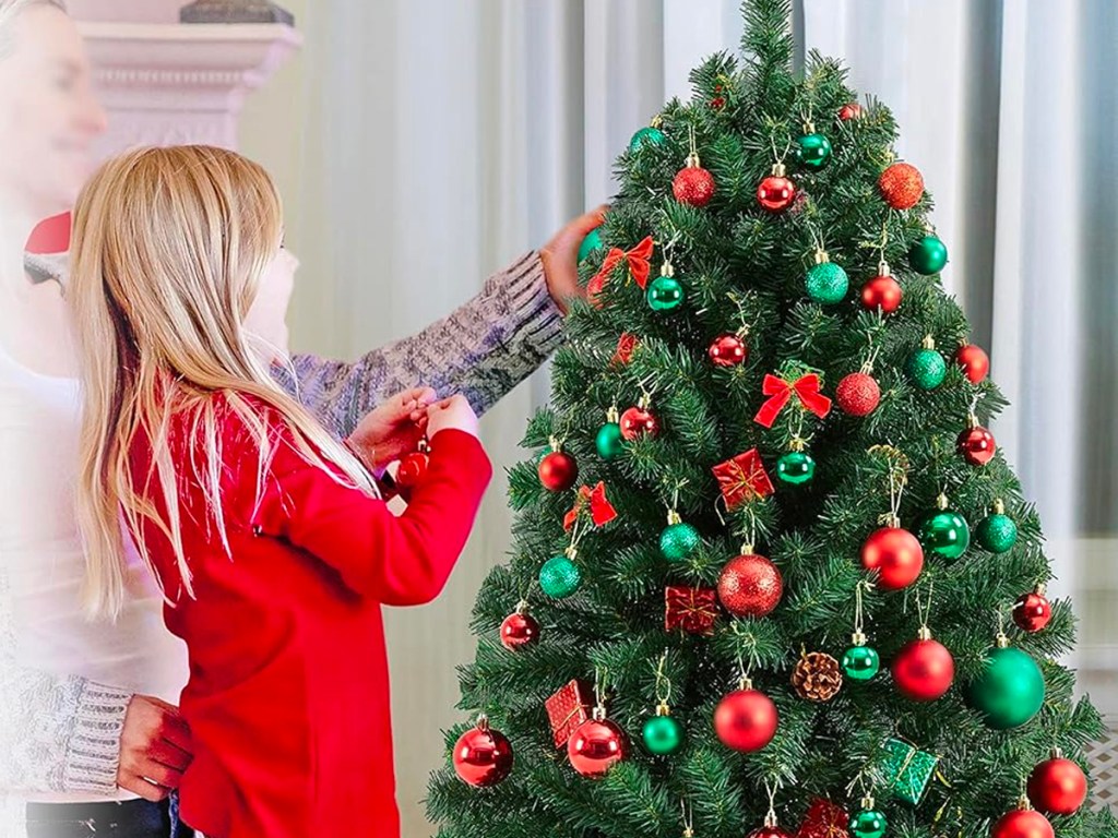 girl putting ornaments on christmas tree