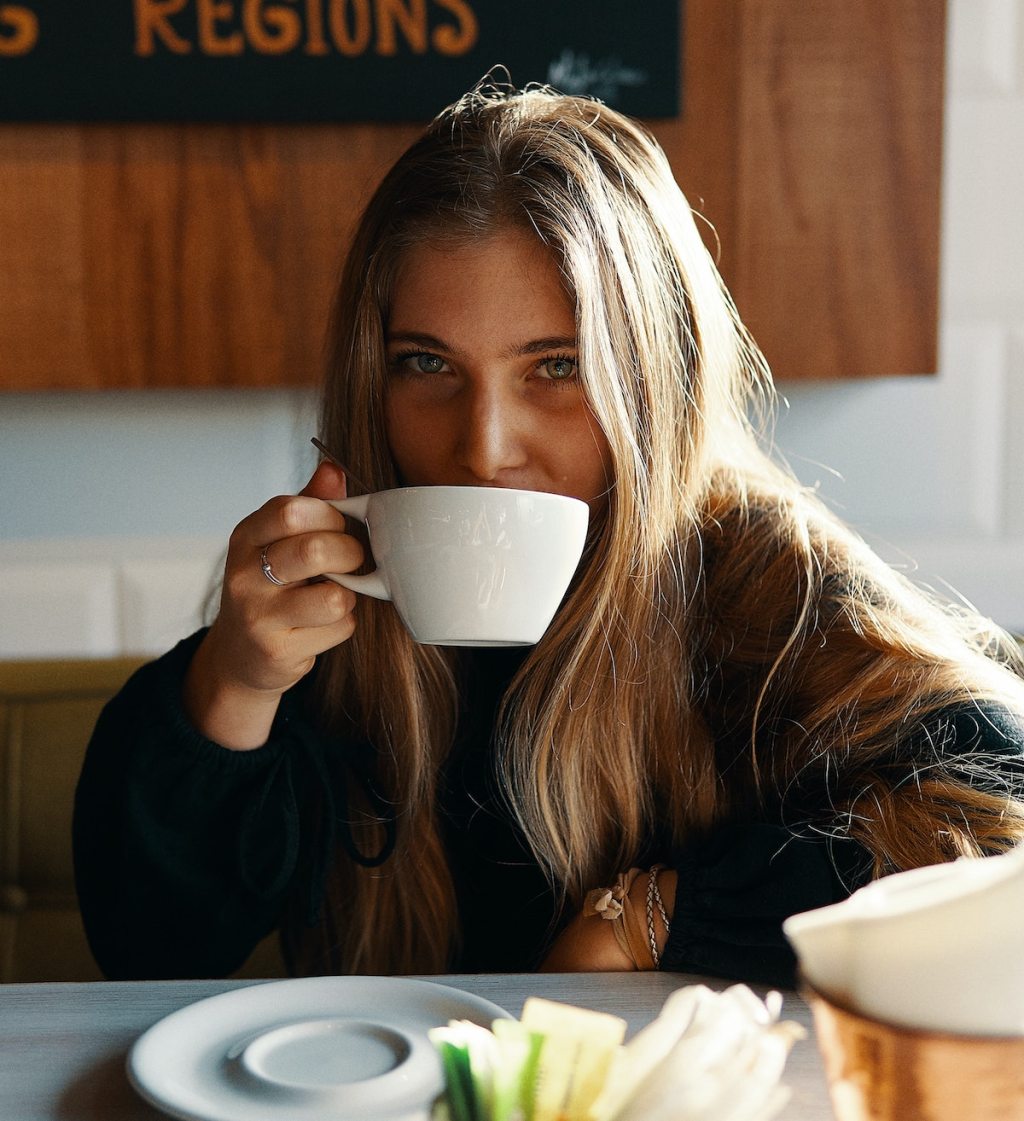 girl sipping from white coffee mug