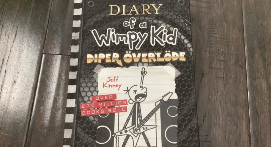 diary of a wimpy kid diner overload hardcover book displayed on top of a wood floor-2