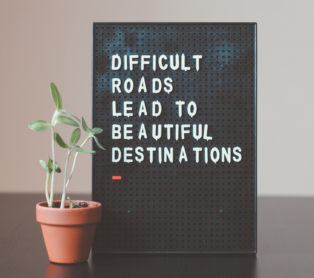 difficult roads lead to beautiful destinations letter board next to plant