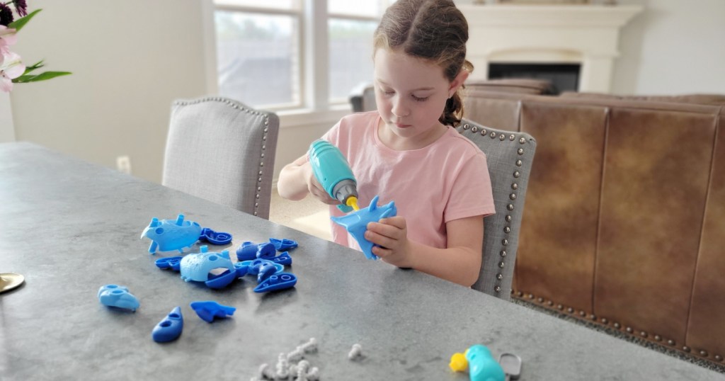 girl playing with a dinosaur toy building set