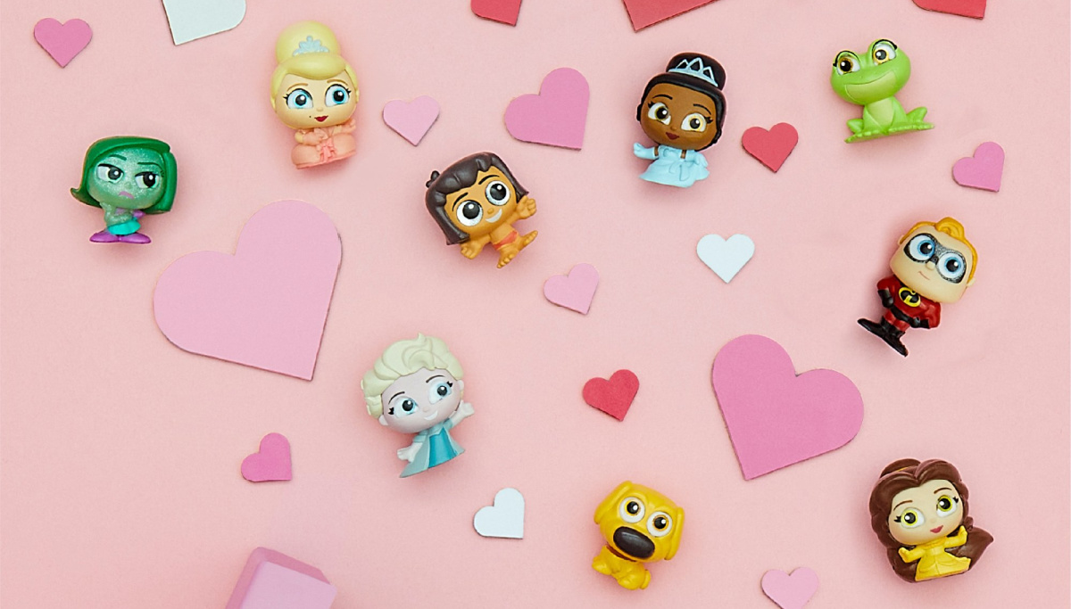 disney doorables figures laid on a pink surface surrounded by paper hearts