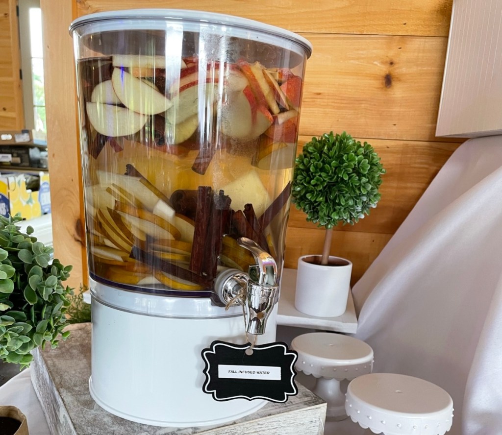 apples, cinnamon, and water in a drink dispenser