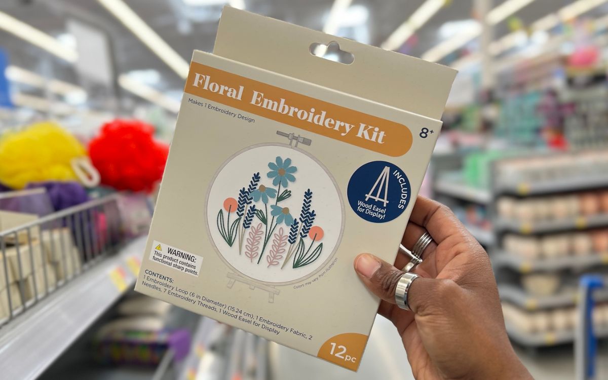 a womans hand holding a DIY floral embroidery kit