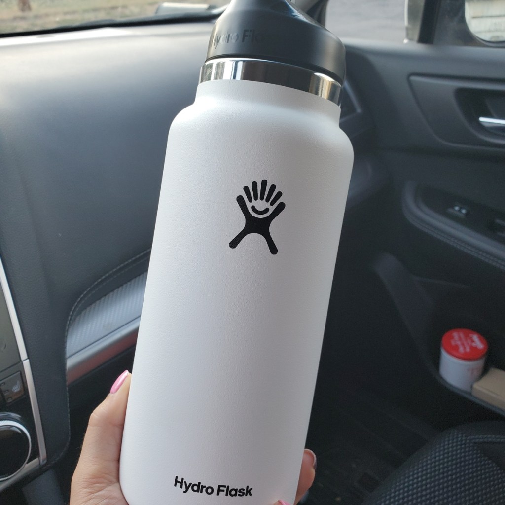holding a white Hydro Flask bottle