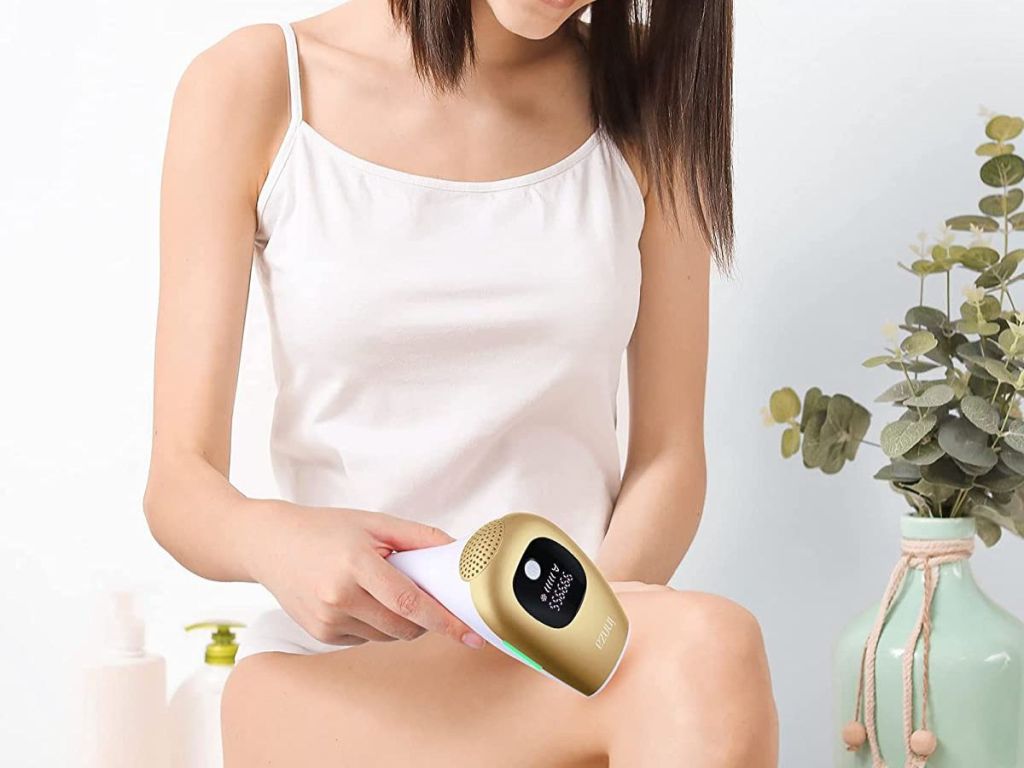 woman using gold hair removal device on legs