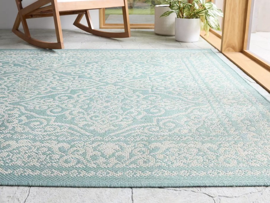 patio space with light aqua green medallion print rug and tan furniture