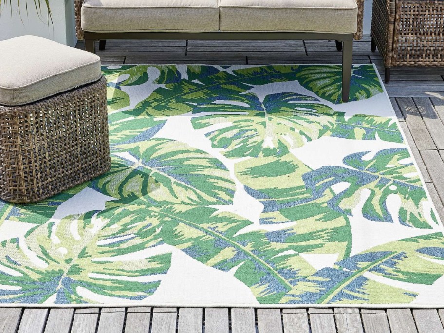 outdoor space with large palm leaf print outdoor rug and tan wicker furniture