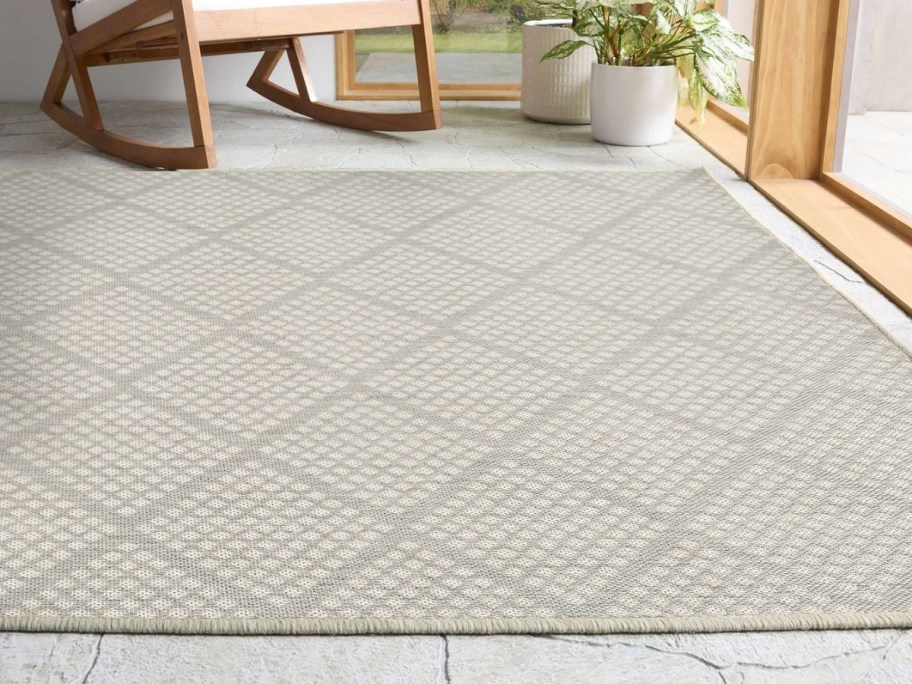 large outdoor rug in tan with a diamond print on a pack patio